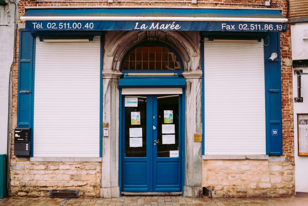 Street photography in Brussels on a rainy day – blue storefront with closed shutters and stone façade