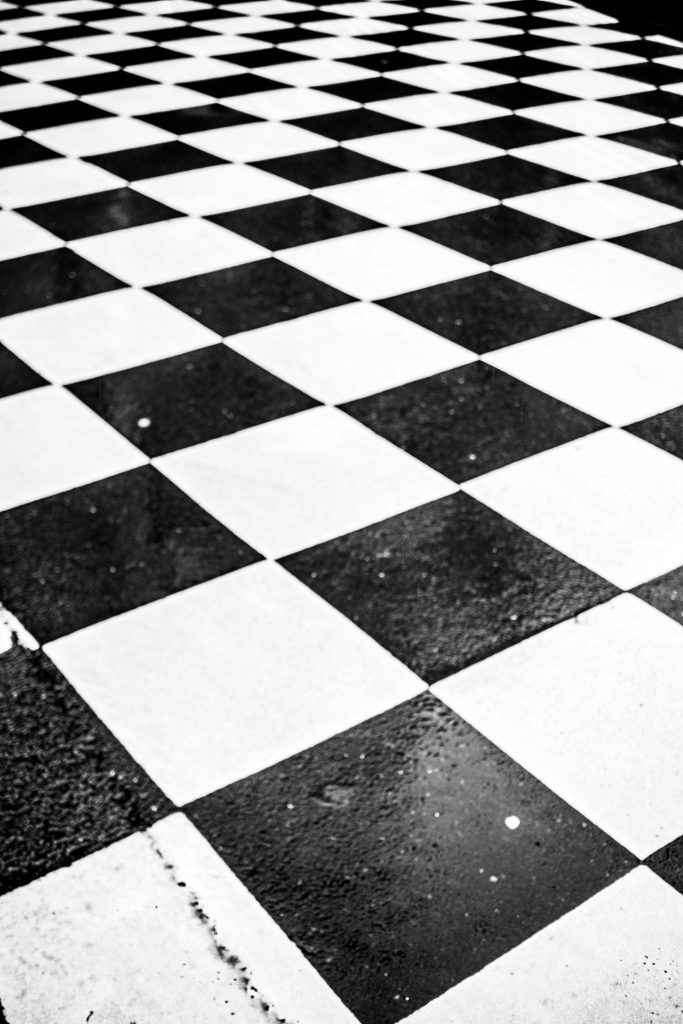 Street photography in Brussels on a rainy day – black and white checkered pavement with wet reflections