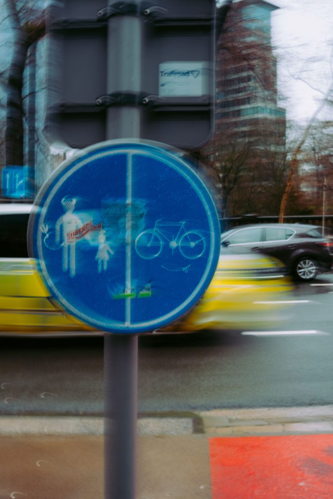 Street photography in Brussels on a rainy day – pedestrian and bicycle lane sign with motion blur from passing taxi