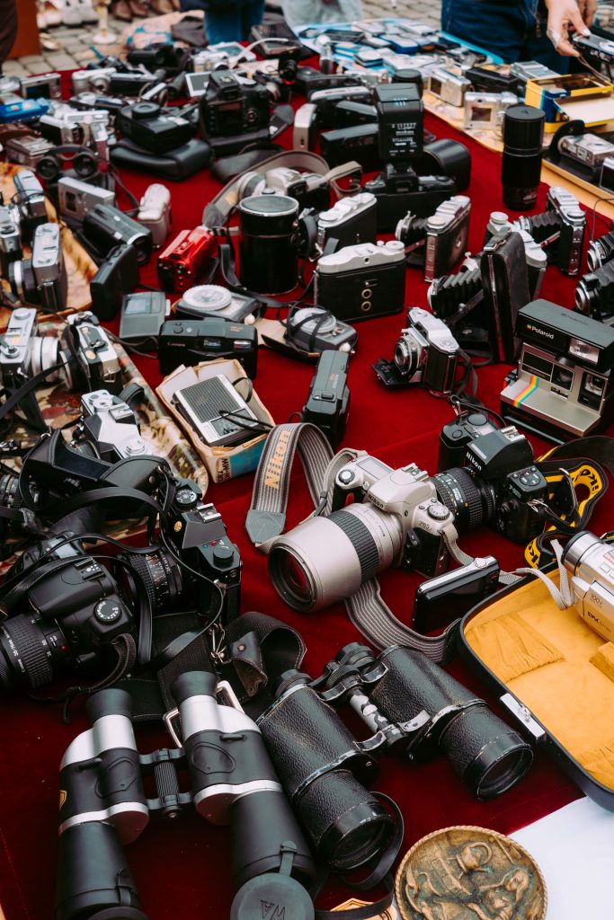 Table filled with vintage cameras and binoculars at a Brussels flea market.