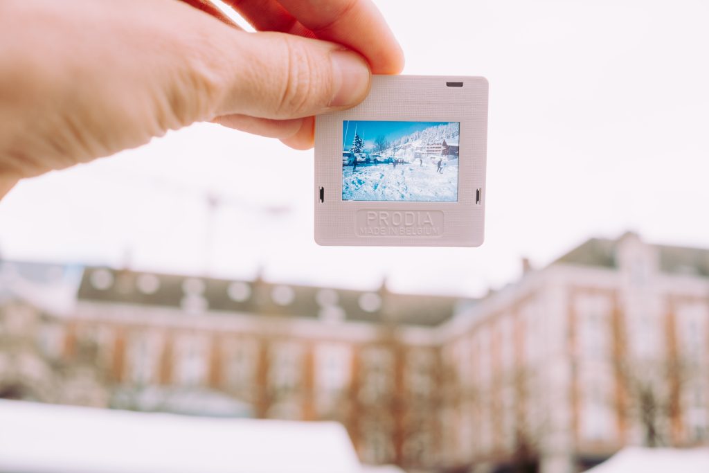 Hand holding a small photo slide with snowy mountain scene at Place du Jeu de Balle flea market.