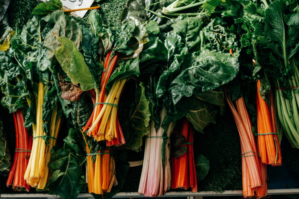 Bundles of colorful swiss chard vegetables hanging at fresh produce stall in Ixelles Brussels