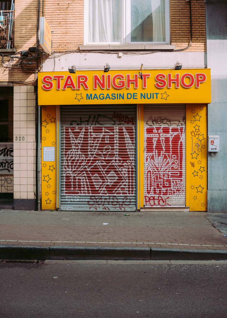 bright yellow night shop storefront with graffiti shutters in Ixelles Brussels street photography