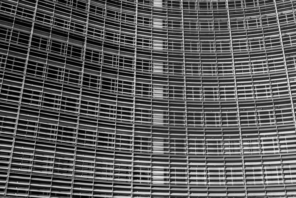 Extreme close-up black and white photograph of the Berlaymont building facade in Brussels European Quarter showing angled aluminium louvres and window frames as an abstract repeating grid
